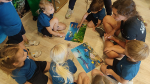 Children sitting in circle studying ocean images.