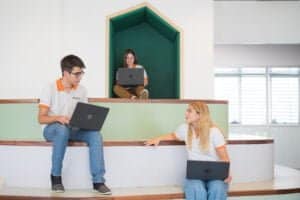 Students talking with each other while studying with their computers