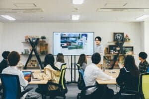 Studens in classroom. All heads turned listening to the teacher displaying content on the screen.