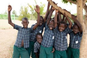 Kids playing with a tree, laughing and looking at the camera.