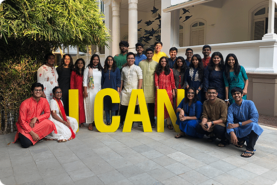 Group of students and staff posing around large yellow “I CAN” letters at school, celebrating confidence and community.