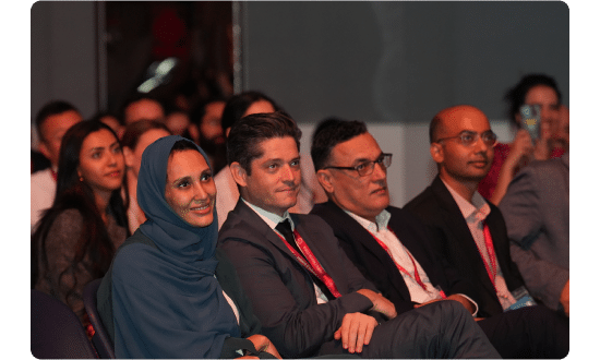 Audience members attentively listening and smiling during a session at the World Schools Summit.