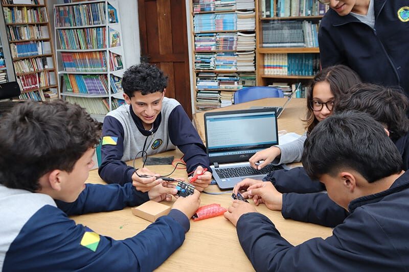 Group of students working collaboratively on electronics and coding project in a school library