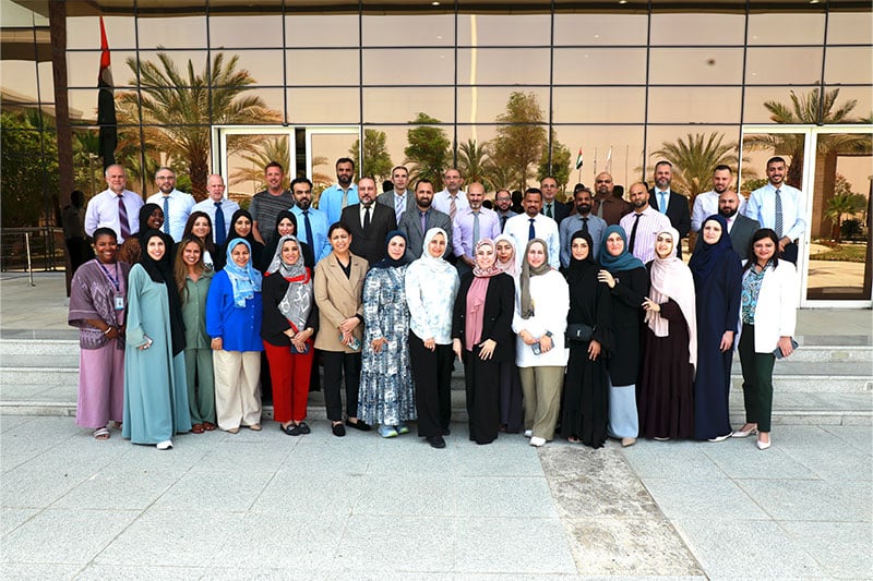 Group photo of ATS UAQ Campus staff and educators outside the main school building in Umm Al Quwain, UAE
