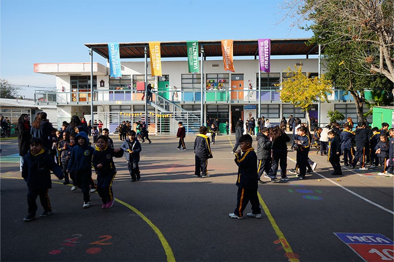 Students at Colegio Carlos Oviedo playing in a vibrant school courtyard with colorful banners overhead