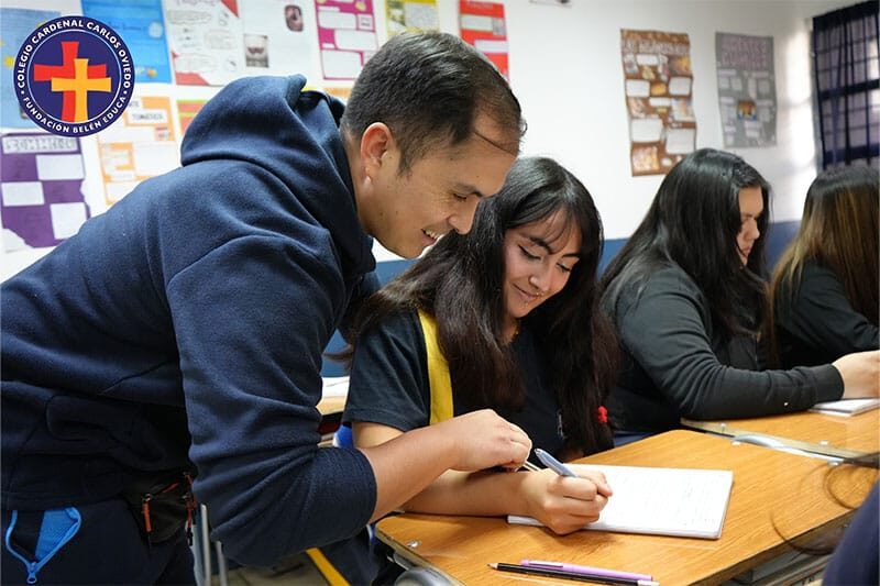 Teacher assisting a student during a classroom activity at Colegio Carlos Oviedo