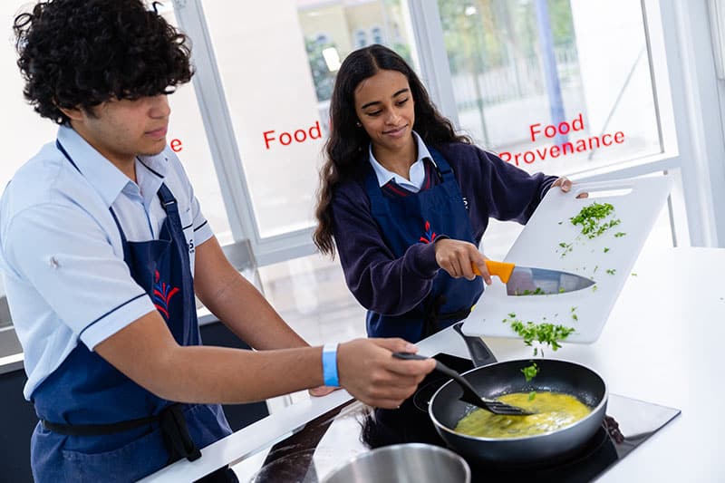 Two students cooking together in a modern food tech classroom
