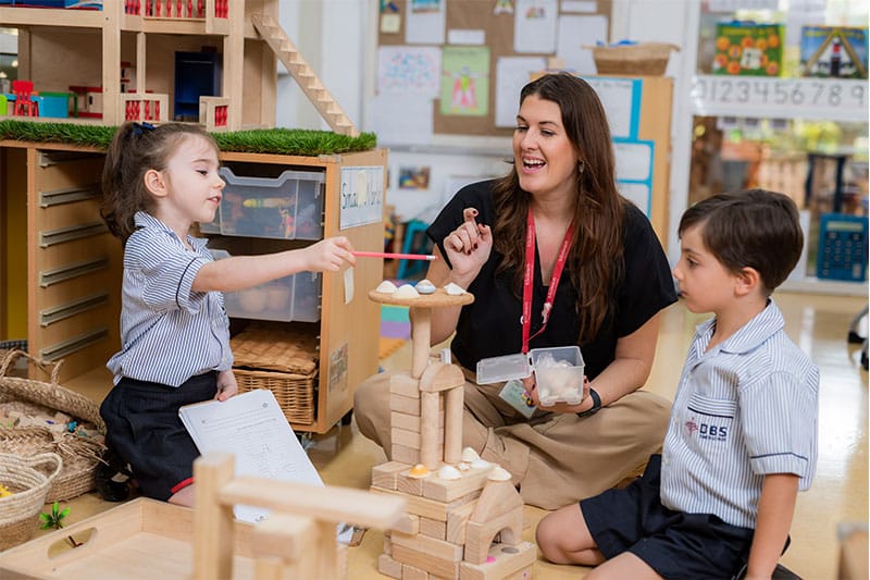 Teacher and young children interacting with building blocks and natural materials