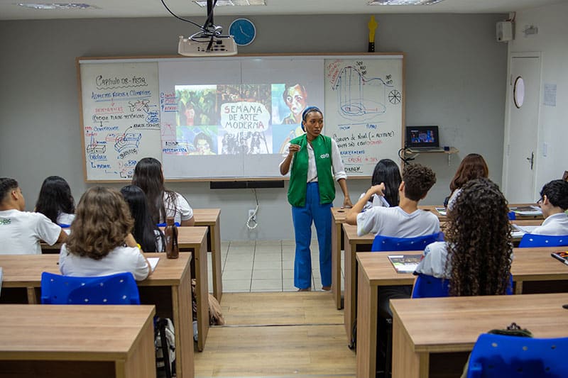 Teacher presenting a lesson to high school students during a modern art class at Escola COC São Luís.