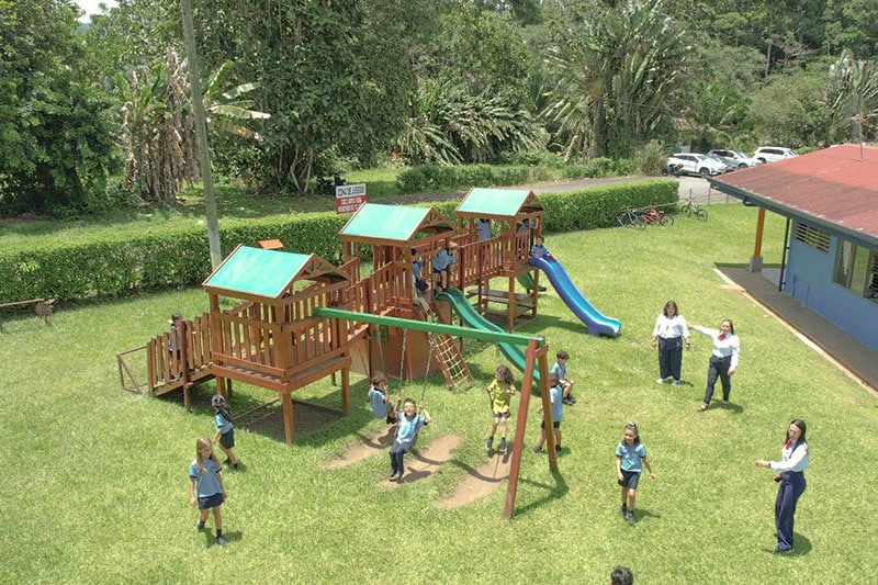 Young students playing on a wooden playground set during recess at Escuela y Colegio Científico Interamericano