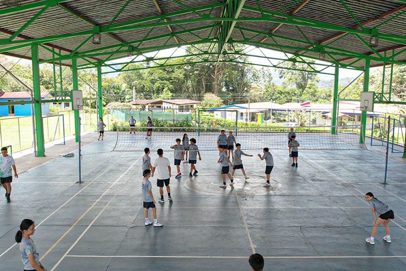 Students playing volleyball in a covered sports court at Escuela y Colegio Científico Interamericano