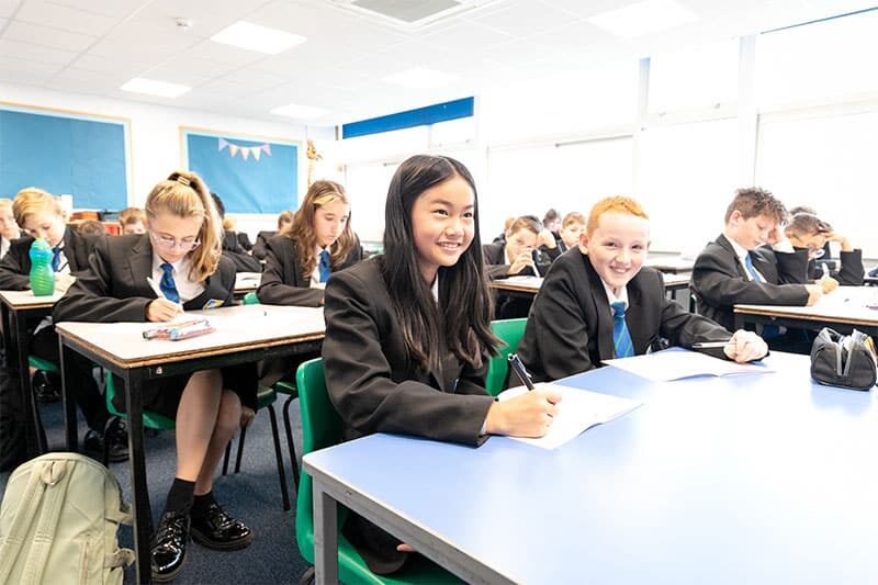 Secondary students in classroom smiling during a lesson