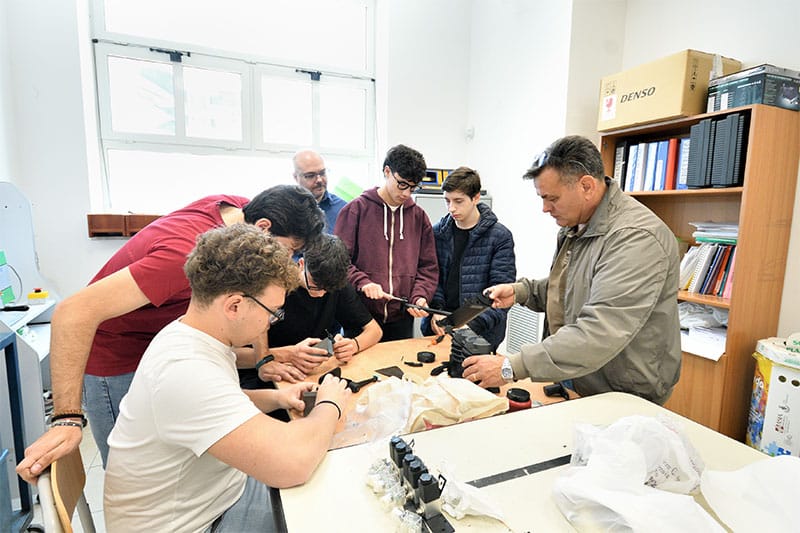 Teacher and students assembling mechanical components in a workshop