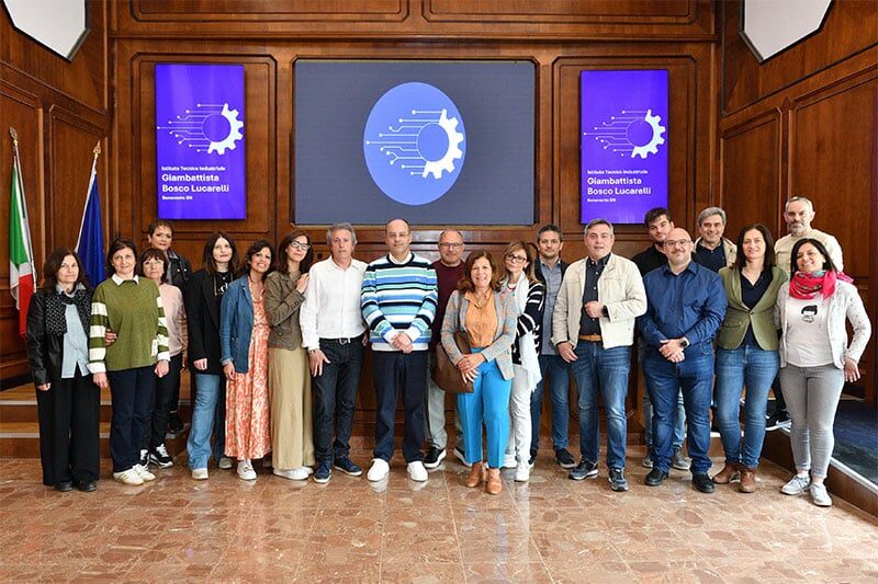 Group photo of staff members in an auditorium with digital signage