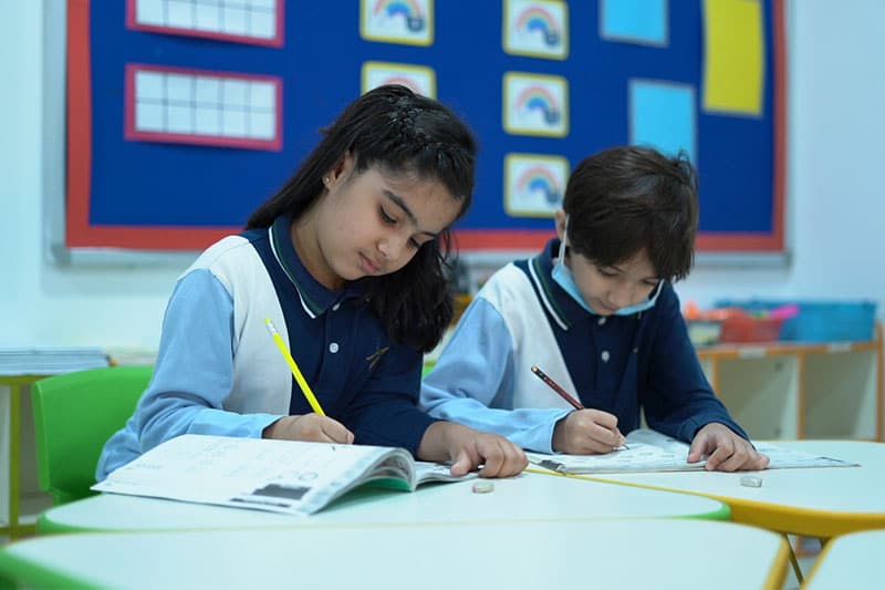 Young students focused on writing assignments in a brightly decorated classroom