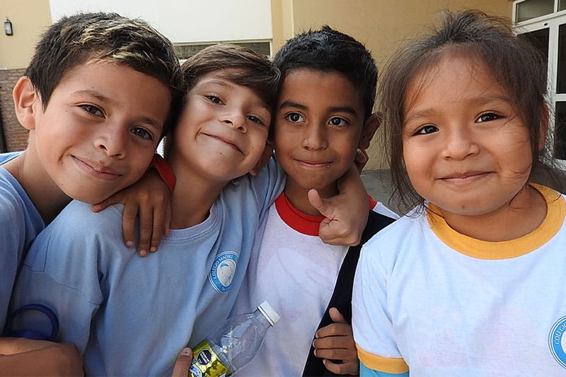 Group of smiling young students in school uniforms posing together outdoors