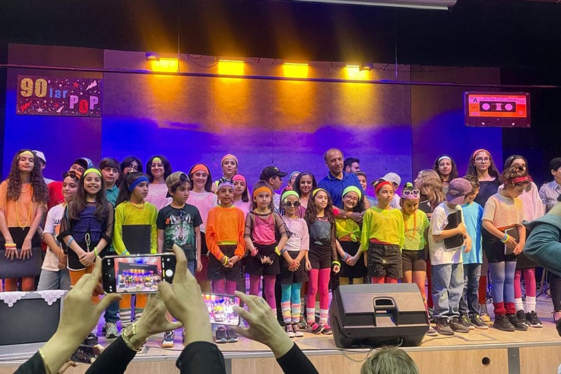Students performing live music on stage at Diyarbakir Science and Art Center with band and audience