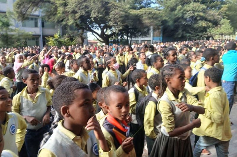 Large group of students in yellow uniforms participating in a school assembly