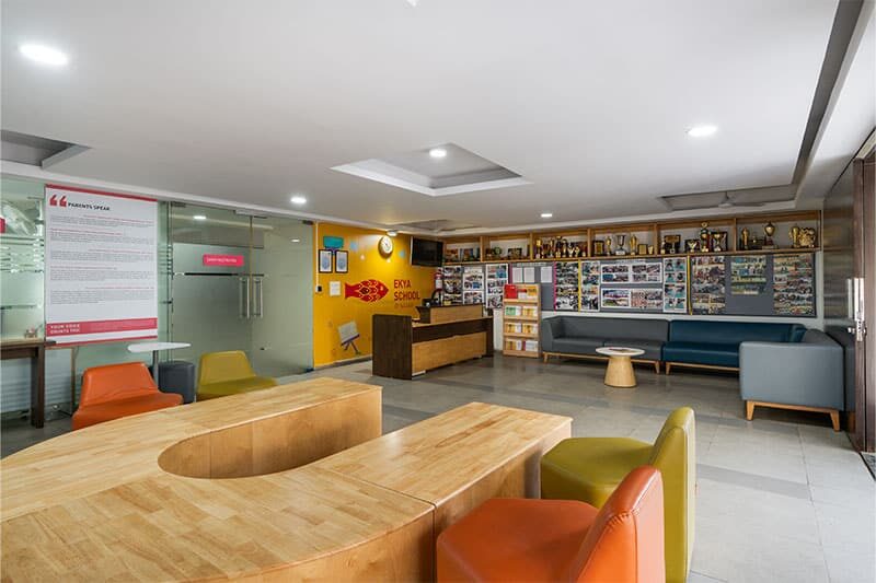 Reception area at Ekya School, J P Nagar showcasing awards, photos, and modern seating