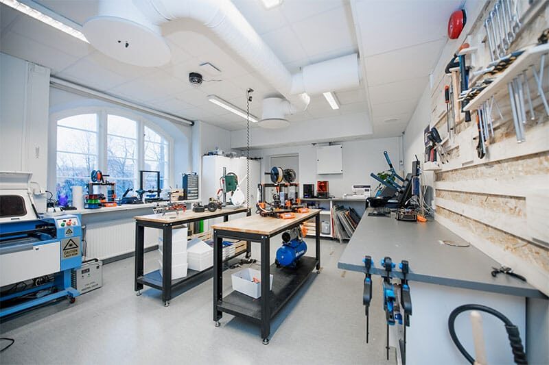 Modern school makerspace with tools, 3D printers, and workstations for student innovation