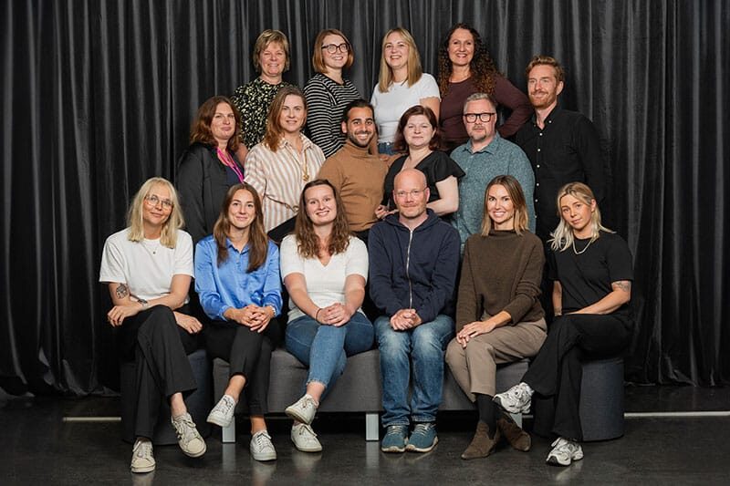 Group photo of NTI Gymnasiet Johanneberg staff in front of a dark curtain backdrop