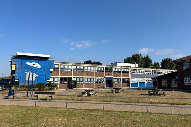 Front view of Rivers Academy West London with mural and student outdoor seating area