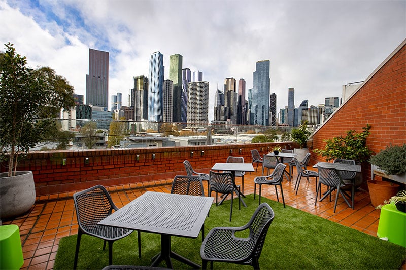 Outdoor terrace with tables and chairs overlooking a modern city skyline
