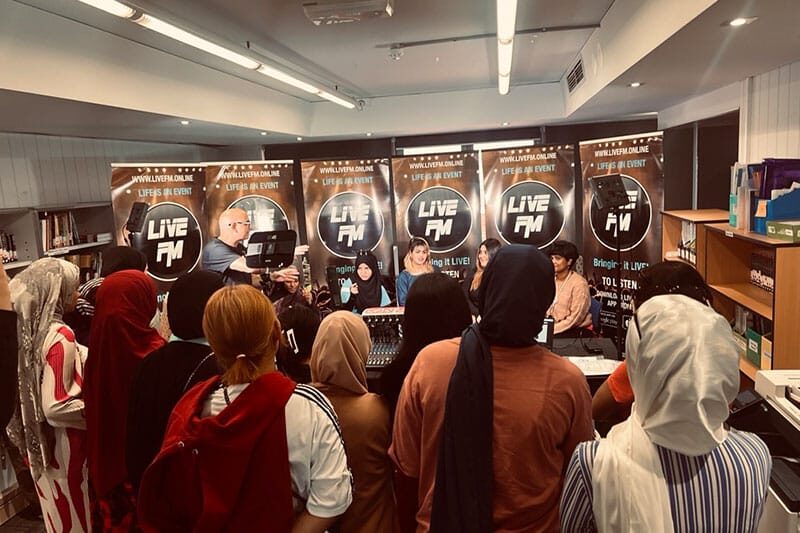 Students observing a live radio broadcast at a Live FM studio event