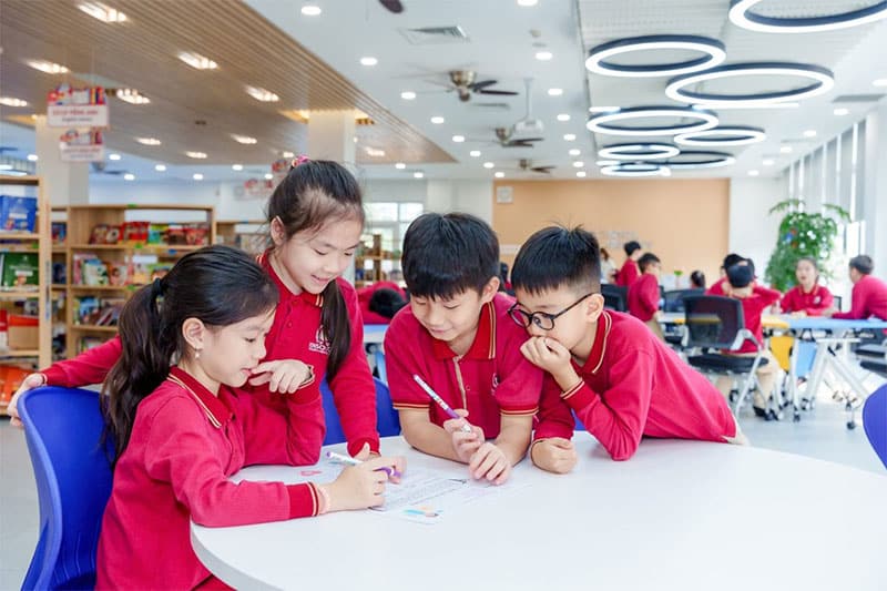 Primary students engage in a group activity in the school library, fostering collaboration and communication.