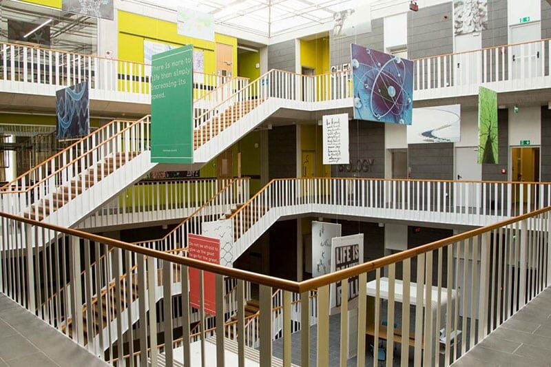 Interior of VKV Koç Özel Okulu featuring staircases and educational artwork