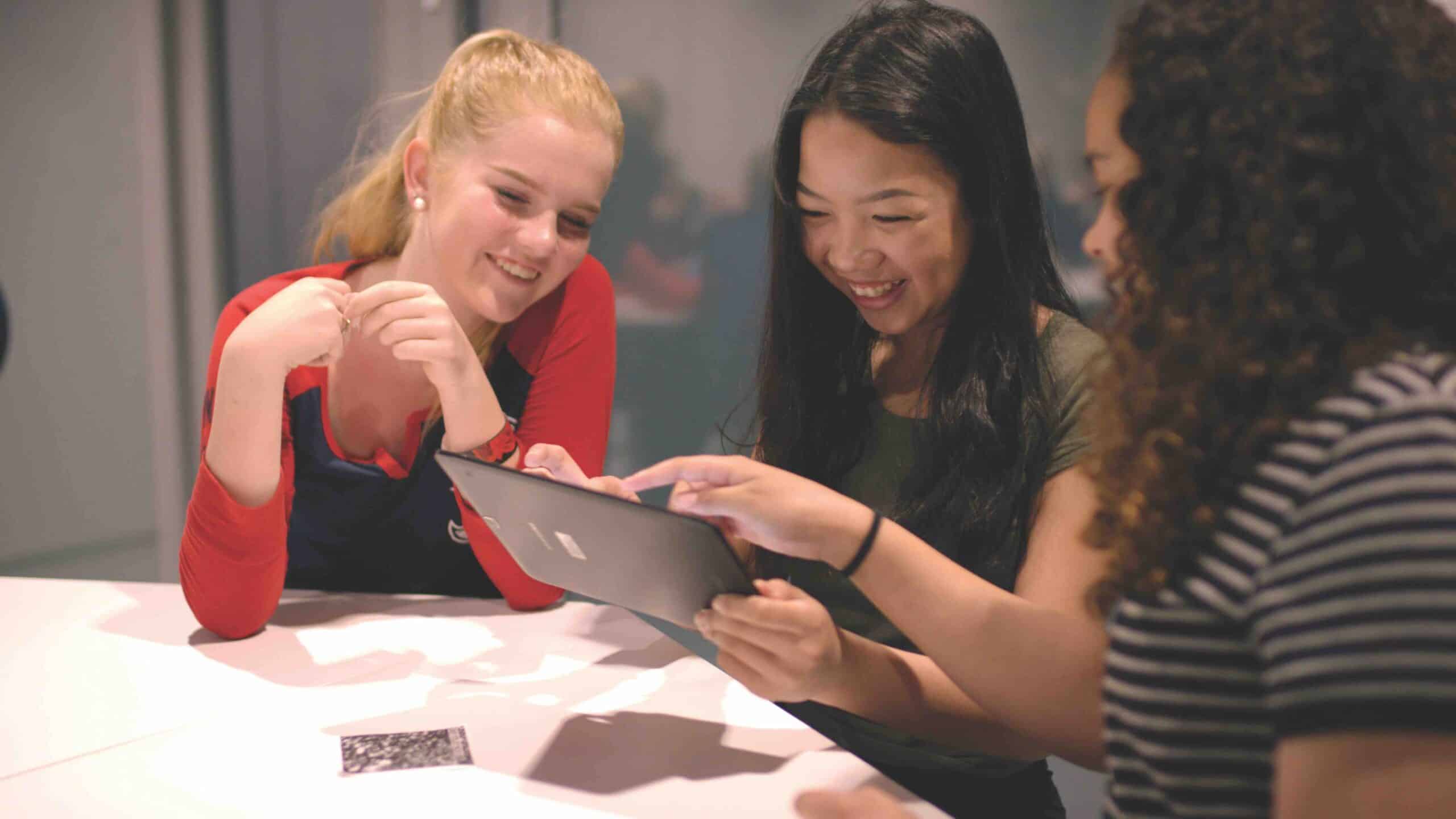 Group of Students Smiling and Collaborating While Using a Tablet