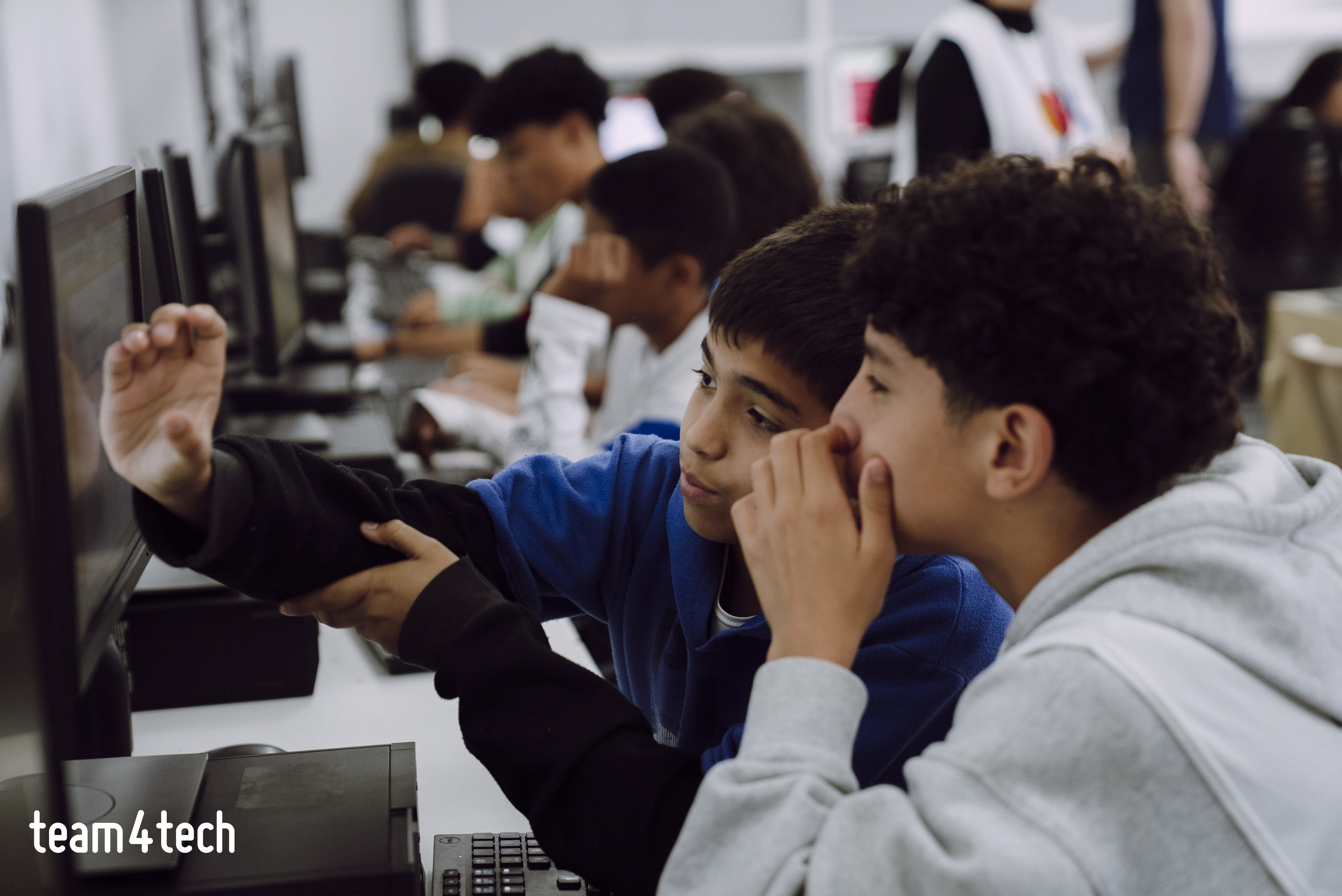 Two students collaborating on a computer in a classroom during a technology workshop