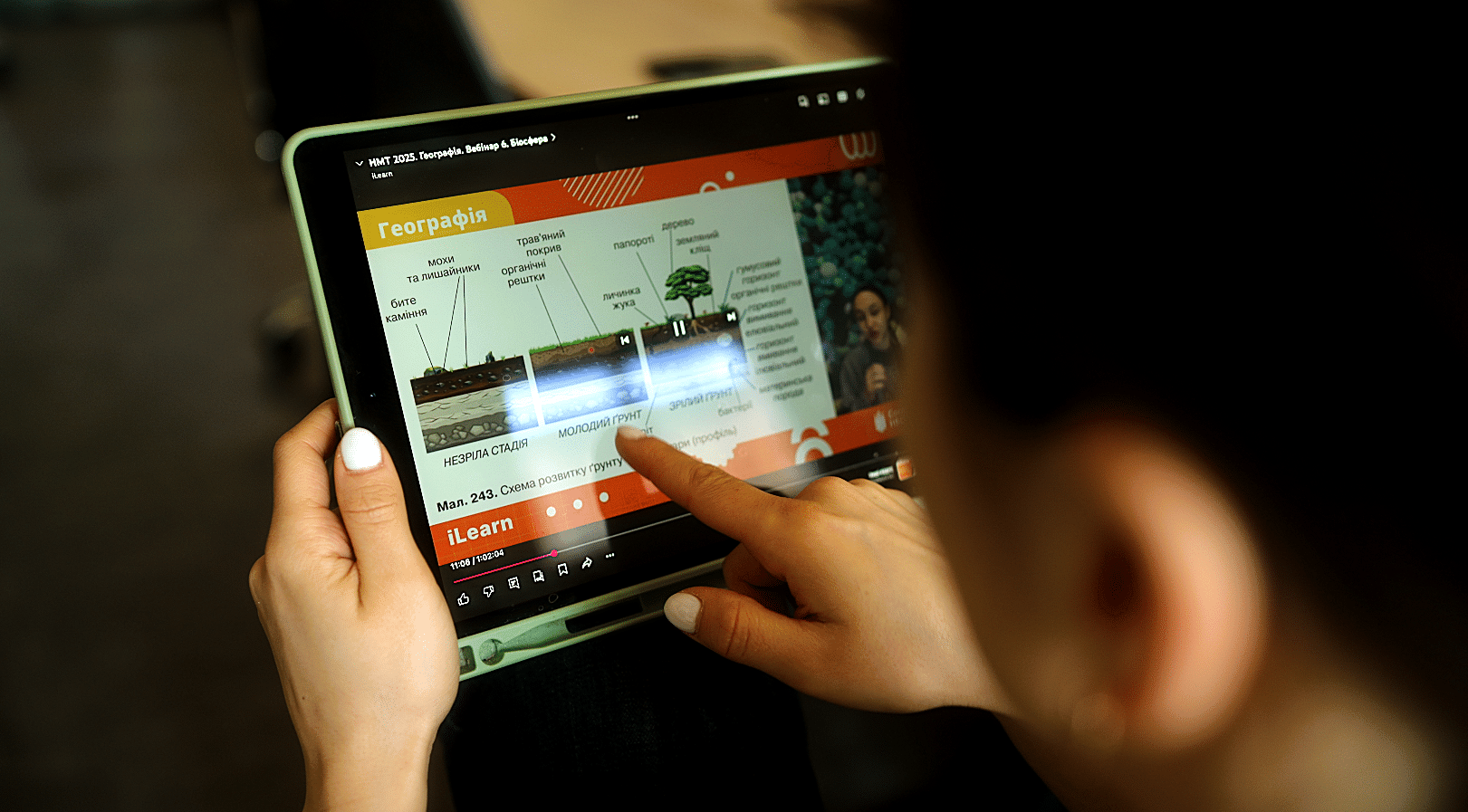 Student using a tablet to watch an educational video on geography in Ukrainian language