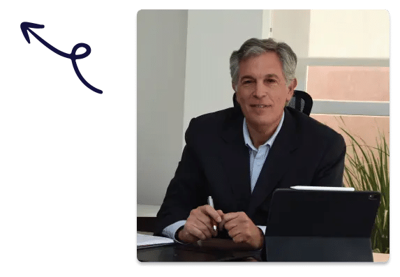 Businessman smiling at his desk with a tablet and pen, arrow pointing to him