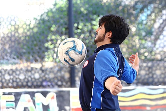 Football player performing a header during a game Person playing football, juggling the ball with their head on a sports field
