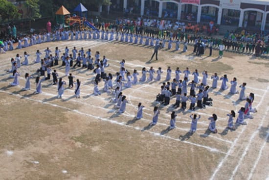 Students performing a synchronized group formation on a school playground during a sports day event.