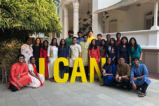 Group of young students posing with large yellow letters spelling I CAN during a school event.