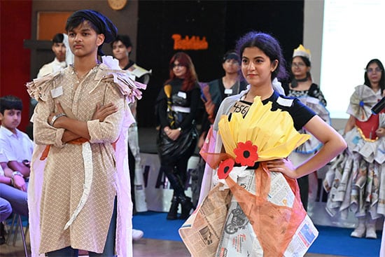 Students showcasing creative outfits made from newspaper during a fashion show event