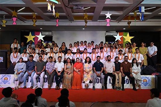 Group photo of students and faculty at an event, with decorated stars and colourful hanging decorations in the background
