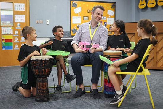 Music lesson with teacher and children playing drums and instruments Teacher and children playing drums and musical instruments in a classroom