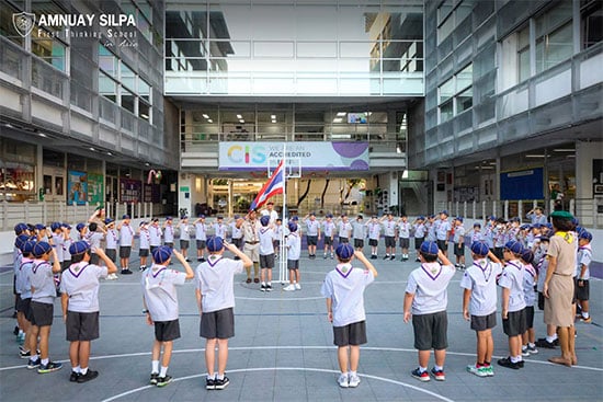 Young students take part in scout flag ceremony at school Primary school students in scout uniforms participating in a flag ceremony at school courtyard.