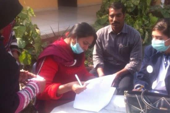 Health worker wearing a mask registering people during a community medical camp.