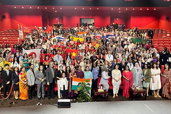 Large group photo of international participants holding country flags at a global education conference.