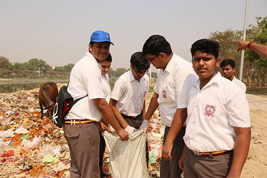 Group of students picking up garbage in a field during a clean up drive