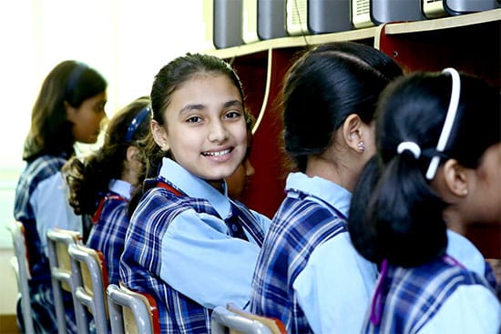 Smiling student in a school computer lab A young girl smiling in a school computer lab with classmates sitting at computers
