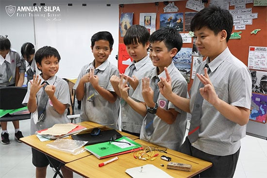 Students present science project during classroom activity Group of school boys presenting a science project in the classroom with smiles and hand gestures.