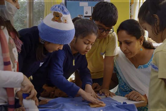 Teacher guiding young students in a hands-on classroom activity with fabric and wooden blocks.