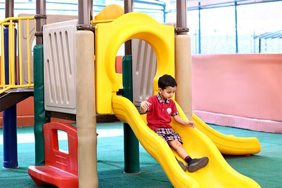 Child playing on a colourful playground slide Child sliding down a yellow playground slide