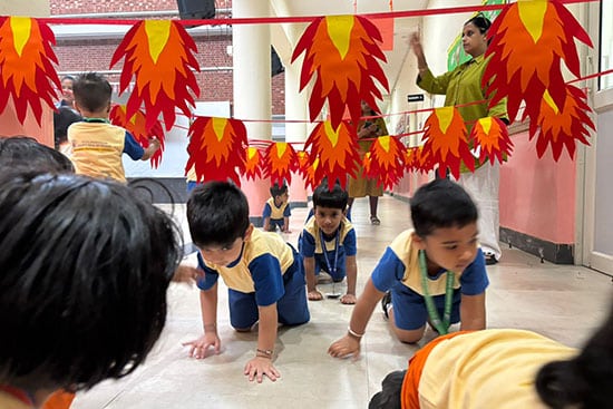 Children crawling under colourful paper flames during a playful activity in a classroom
