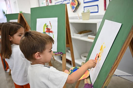 Kids engaged in creative painting activity in a classroom setting Children painting on easels in a bright classroom